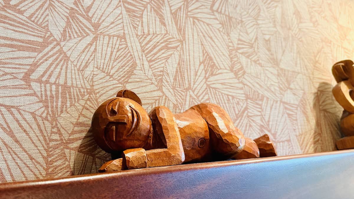 Wooden baby doll lying on a shelf, detailed craftsmanship, decorative home decor piece.